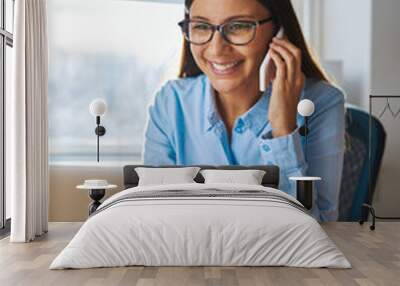 Smiling woman on phone behind laptop Wall mural