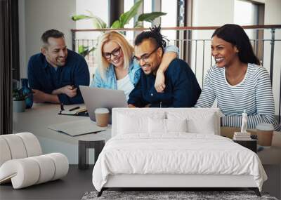 Smiling work colleagues laughing together during an office meeti Wall mural