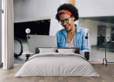 Smiling young African female entrepreneur working and listening Wall mural