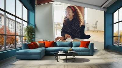 Smiling young businesswoman at work at her office desk Wall mural