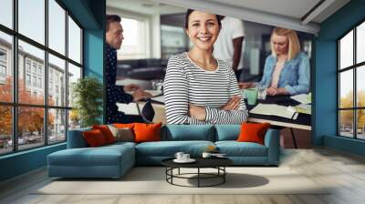 Smiling young businesswoman sitting with colleagues in an office Wall mural