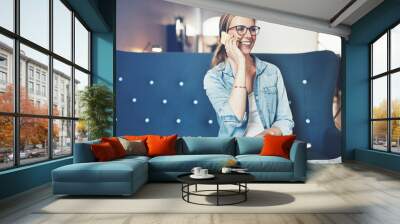 Smiling young businesswoman talking on her cellphone and working online Wall mural