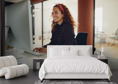 Smiling young businesswoman working late in her office Wall mural