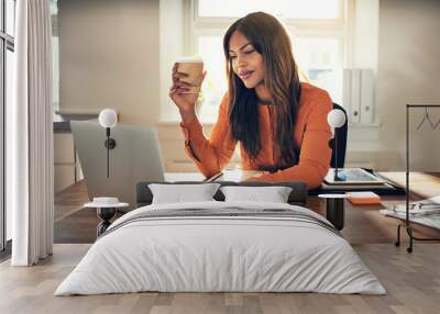 Smiling young entrepreneur working in her home office drinking c Wall mural