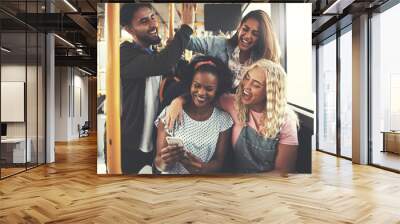 Smiling young friends using a cellphone together on the bus Wall mural