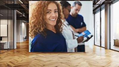 Smiling young medical intern standing with doctors in a hospital Wall mural