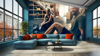 Smiling young people sitting in a gym after working out Wall mural