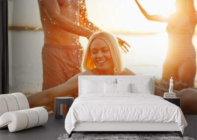 Smiling young woman and friends splashing water in a lake Wall mural