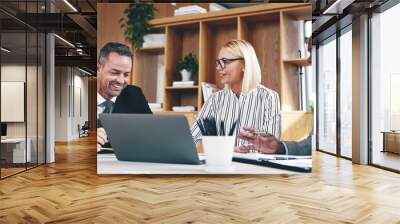 Three diverse businesspeople laughing while working together in an office Wall mural