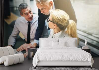 Three mature businesspeople discussing work and using on a lapto Wall mural