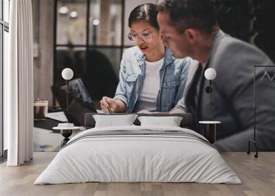 Two businesspeople sitting at a table and going over paperwork Wall mural