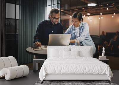 Two diverse young businesspeople working on a laptop Wall mural