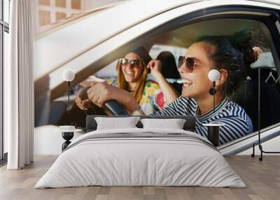 Two laughing young girlfriends driving on a road trip together Wall mural