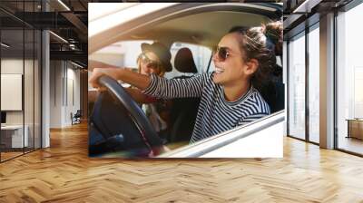 Two laughing young girlfriends driving together in a car Wall mural