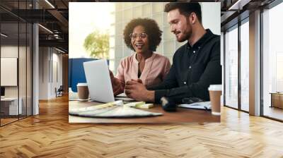 Two smiling businesspeople sitting in an office using a laptop Wall mural