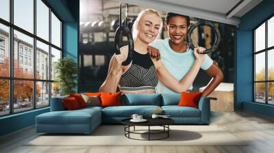 Two smiling friends working out with rings at the gym Wall mural