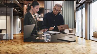 Two young businesspeople going over paperwork at an office table Wall mural