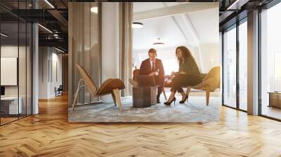 Two young businesspeople working together on an office laptop Wall mural