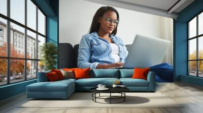 Young African woman relaxing at home using a laptop Wall mural