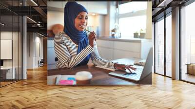 Young Arabic female entrepreneur working from home in her kitche Wall mural