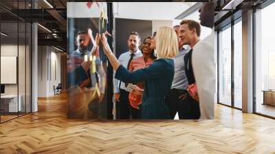 Young businesswoman and her team brainstorming with sticky notes Wall mural