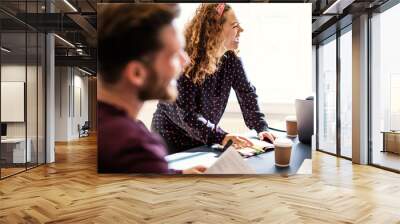 Young businesswoman laughing with coworkers during an office mee Wall mural