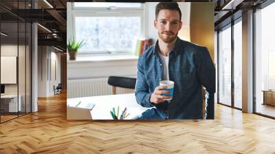 Young entrepreneur sitting in his office Wall mural