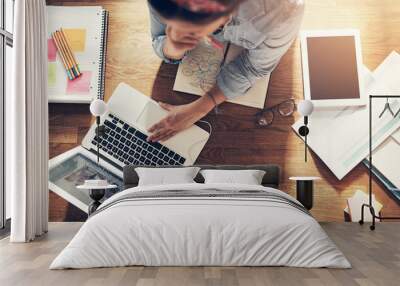 Young female entrepreneur thinking and browsing laptop in office Wall mural