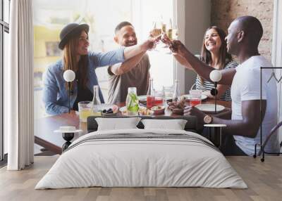 Young group of smiling friends clinking glasses Wall mural