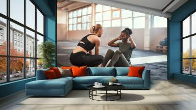 Young woman laughing while doing sit-ups with a  friend Wall mural