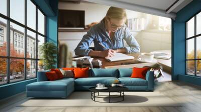 Young woman sketching out ideas in her kitchen at home Wall mural