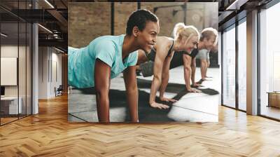 Young woman smiling while doing pushups in an exercise class Wall mural