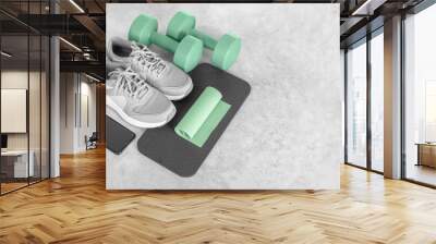 Fitness equipment on a gray concrete background. Sports shoes, smartphone, dumbbells, mat, exercise band, copy space. Fitness and activity. Smart fitness training. Home workout online.  Wall mural