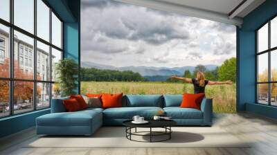 Caucasian woman with arms outstretched soaking in the Great Smoky Mountains in a meadow in Cades Cove Wall mural