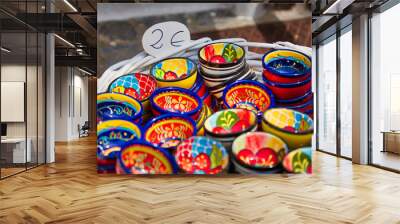 Closeup of a basket of colorful souvenir bowls for sale for 2 Euros at a market in Sagunto, Spain Wall mural