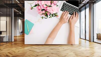 Flat lay home office desk. Workspace with woman hands, laptop, pink peony bouquet, golden accessories, mint diary. Top view Wall mural