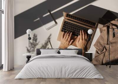 Flatlay of person hands working on laptop computer. Aesthetic bohemian home office workspace. Work at home. Notebook, pampas grass sunlight shadow on table. Flat lay, top view Wall mural