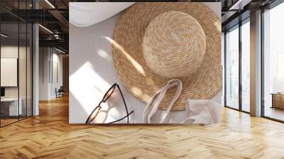 Flatlay of women's fashion accessories. Stylish female sunglasses, straw hat, shopper bag on white lounge couch with pillows. Top view Wall mural