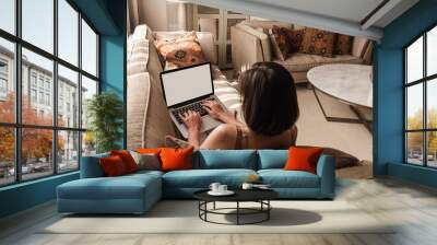 Young beautiful woman work on laptop computer with blank screen. Eastern traditional home interior design concept. Oriental style living room with marble table, sofa, pillows, shutter, decorations Wall mural