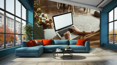 Young woman work on laptop computer with blank display screen with mockup copy space. Modern home living room interior design. Christmas, New Year decorated workspace. Wall mural