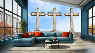 Three weathered stone crosses standing on top of a stone wall under a clear blue sky, symbolizing faith, history, and spirituality Wall mural