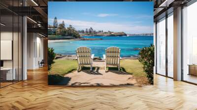 Two white Adirondack chairs on a concrete patio overlooking a beautiful ocean view Wall mural