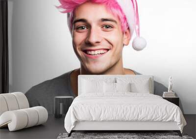 pretty young smiling man with pink hear wearing a santa hat for christmas isolated on a white background as transparent PNG Wall mural