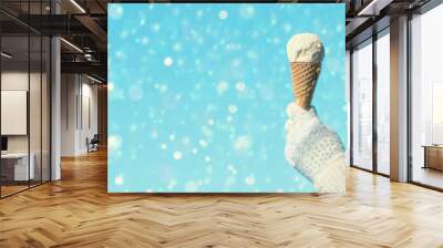 Female hand in knitted gloves with ice cream in a waffle horn on the blured background. Concept.  Wall mural