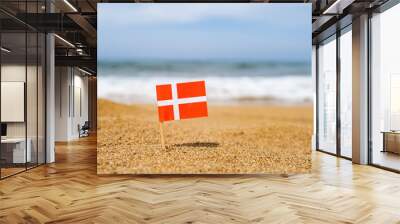 Flag of Denmark in the form of a toothpick in the sand of beach opposite sea wave. Travel concept Wall mural