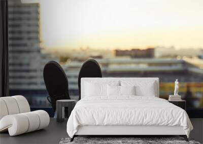 Silhouette of Male feet in shoes on the balcony.  city and sunset background Wall mural