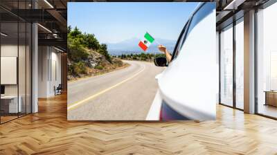 Woman holding Mexico flag from the open car window driving along the serpentine road in the mountains. Concept Wall mural