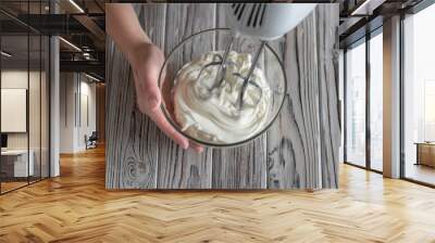 Woman whipping cream using electric hand mixer on the gray rustic wooden table. Flat lay Wall mural