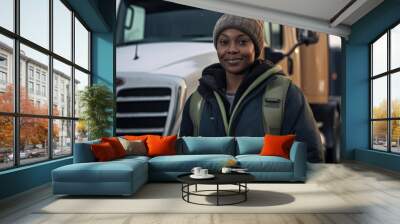 A female african american truck driver in front of her truck during winter Wall mural