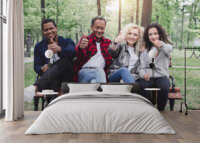 Multiethnic group of happy young people sitting and showing ok gesture Wall mural